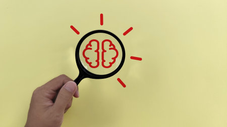 hand holding Magnifying glass with bulb and brain icon on yellow background. idea concept.の写真素材