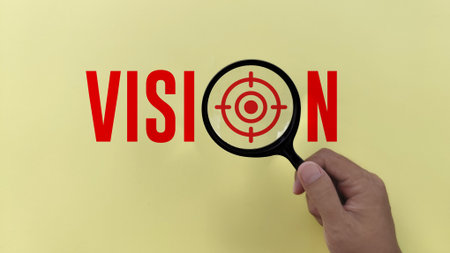 hand holding Magnifying glass with vision text on yellow background. business vision conceptの写真素材