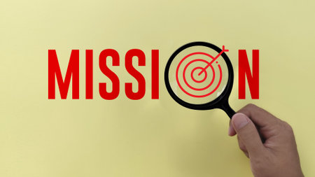 hand holding Magnifying glass with mission text on yellow background. business mission conceptの写真素材