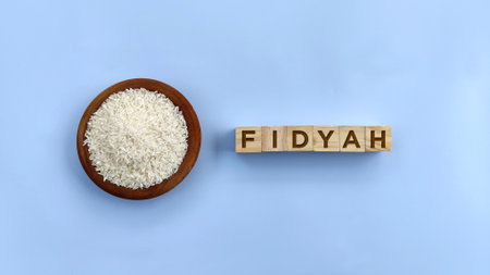 Rice in bowl with Fidyah word against blue background. Fidyah is a charitable made by Muslims who are unable fast during Ramadanの写真素材