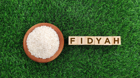 Rice in bowl with Fidyah word against grass background. Fidyah is a charitable made by Muslims who are unable fast during Ramadanの写真素材