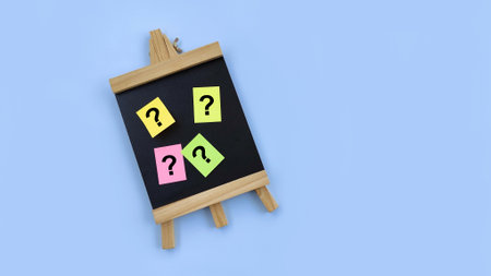 Mini blackboard with question mark on adhesive paper note on blue background. Problems and root cause analysis concept. Research, searching or investigatingの写真素材
