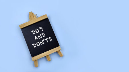 Mini blackboard with word Do's and Don'ts on blue background. Business, guideline, learning conceptの写真素材