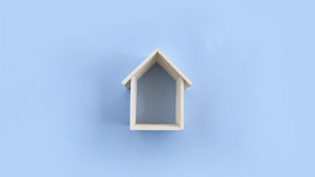 Wooden house frame on blue background. Real estate symbolの写真素材