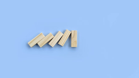 The wooden dominoes are falling. Domino effect stopped by strong piece domino. Insurance, business, risk, management concept.の写真素材