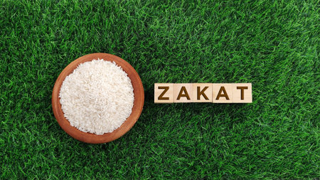 Rice in bowl with Zakat word against grass background. Zakat is  mandatory donation in Islam that distribute wealth to the poorの写真素材