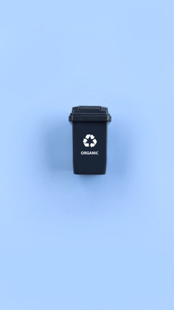 Black recycle bin for separate organic waste isolated on blue background. Recycle conceptの写真素材