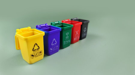 Blue, yellow, green, red and black container for separate plastic, paper, metal and organics bin collection, isolated on the green background. Recycle conceptの写真素材