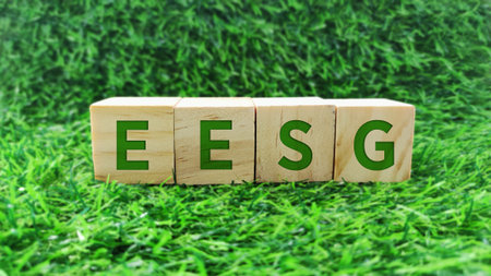 wooden block with EESG, economic, environment, social and governance green text on grass background. sustainability, environmental conceptの写真素材