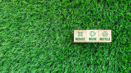 wooden block with REDUCE, REUSE, RECYCLE text and icon on grass background. sustainability, environmental conceptの写真素材