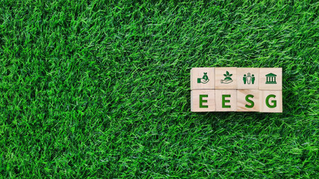wooden block with EESG, economic, environment, social and governance green text on grass background. sustainability, environmental conceptの写真素材