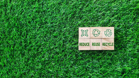 wooden block with REDUCE, REUSE, RECYCLE text and icon on grass background. sustainability, environmental conceptの写真素材