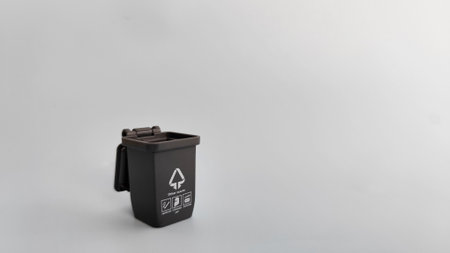 Black recycle bin isolated on grey background. Concept image representing sorting waste materials and promoting sustainable lifestyle practices.の写真素材
