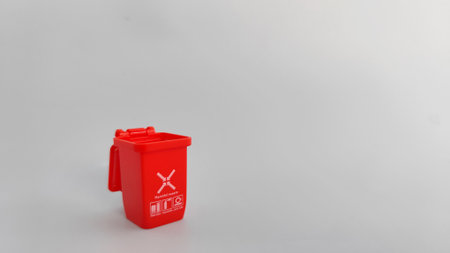 Red recycle bin isolated on grey background. Concept image representing sorting waste materials and promoting sustainable lifestyle practices.の写真素材