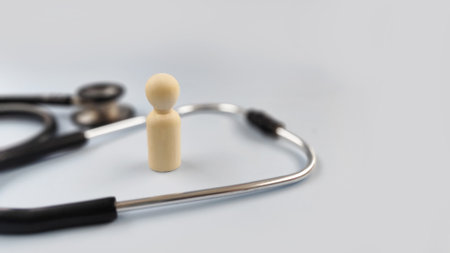 Single wooden figure beside a stethoscope symbolizing individual health, personal medical care, self...