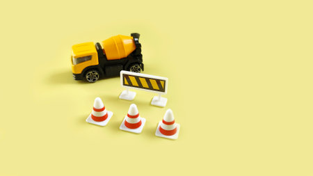 Miniature construction truck with traffic cones and warning sign on pastel background, symbolizing...