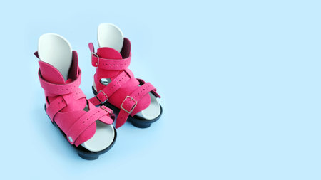 Front view of pink orthopedic boots designed for infant clubfoot correction, isolated on blue background.の写真素材