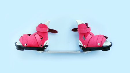 Orthopedic boots connected with bar brace for infant clubfoot correction, viewed from front on blue background.の写真素材