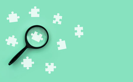 Magnifying glass focusing on puzzle piece representing problem solving, solution search, strategic...