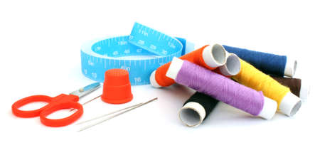 Thread, needles, scissors, thimble, ruler on a white 
