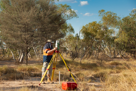 Surveyor with EDM Leica theodolite working in extreme conditions in the Australian outbackのeditorial素材