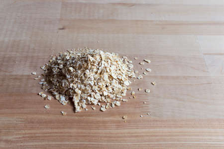 Oatmeal grains on wooden desk. Bright and natural light and shadows
