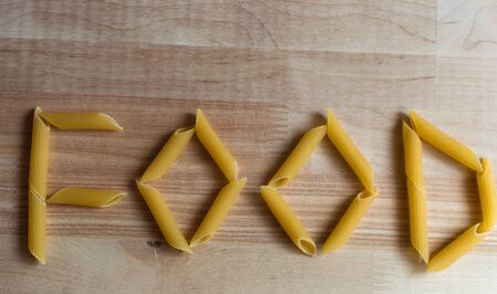 Raw italian pasta on wooden desk form word FOOD. Natural lightの写真素材