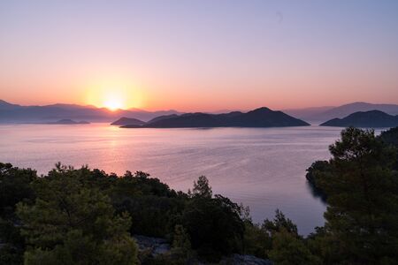 Sunrise over bay in Turkey with calm light and still water. Mountains at the horizonの写真素材