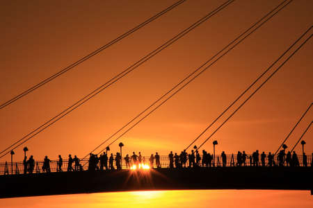 people appreciates the sunset on the bridge