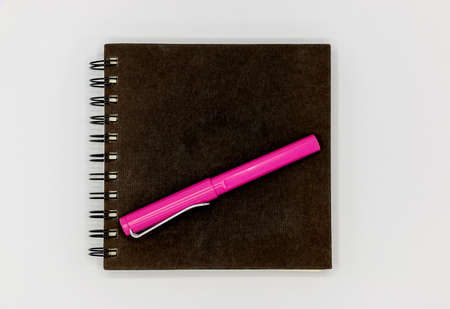 Notebook black color and pink pen white backgroundの写真素材