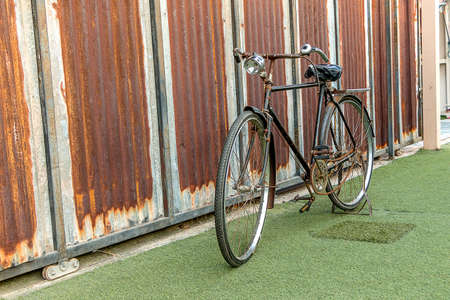 Old bicycle on grass and zinc wallの写真素材