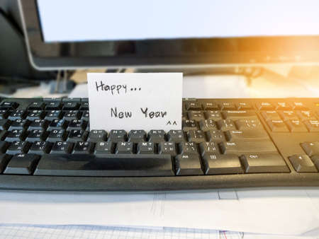 Happy new year white card placed at the computer boardの写真素材