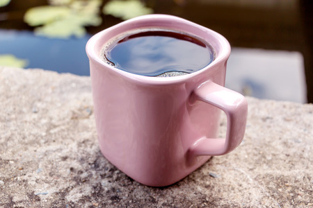 Hot coffee in a pink glass placed on a concrete floor.