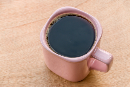 Hot coffee in a pink glass placed on wood tableの写真素材