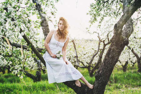 Portrait of beautiful romantic lady in a wreath of apple trees in the summer gardenの写真素材