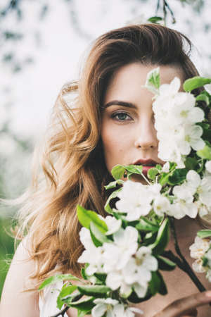 Portrait of beautiful romantic lady in a wreath of apple trees in the summer gardenの写真素材