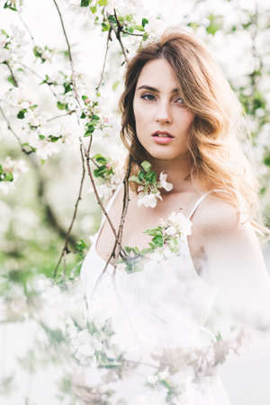 Portrait of beautiful romantic lady in a wreath of apple trees in the summer gardenの写真素材