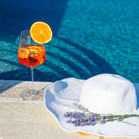 Closeup image of white hat and cocktail near swimming pool, summer vacation conceptの写真素材