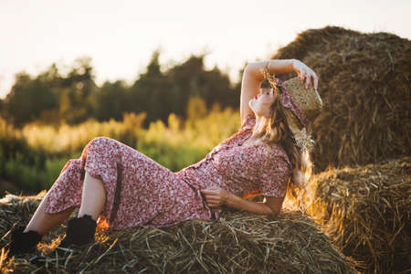 Beautiful young woman on a haystack at sunset