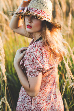 Beautiful woman in field at summer sunsetの写真素材
