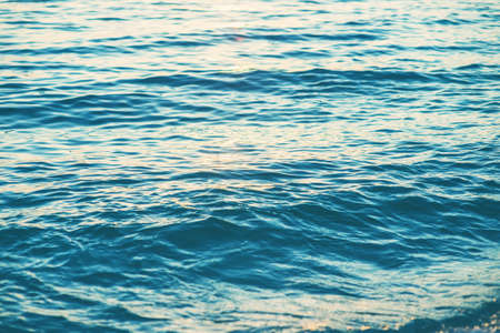 Sea waves and ripples at sunset backgroundの写真素材