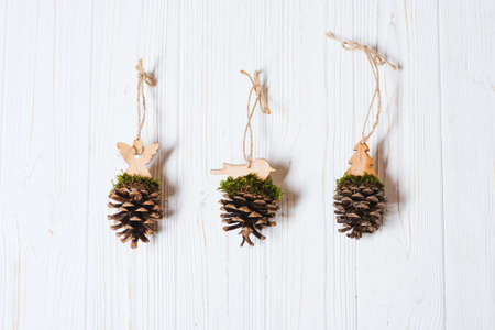 Three handmade Christmas tree toys made of pine cone on white wooden backgroundの写真素材