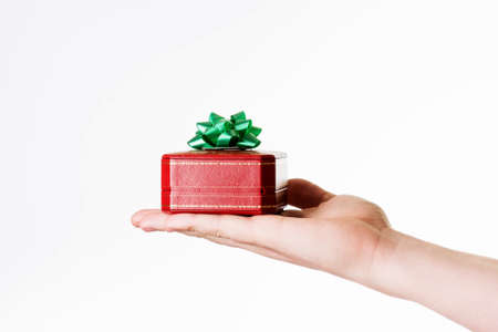 Small red gift box with green ribbon bow in hand, isolatedの写真素材