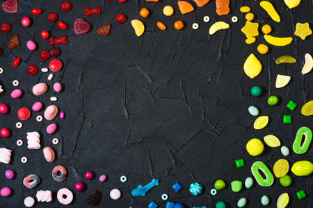 Colorful candies, jelly and marmalade frame shape on dark background. Top view with copy spaceの写真素材