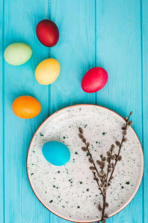 Easter eggs in plate on blue wooden table background