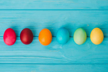 Row of Easter eggs on blue wooden table background