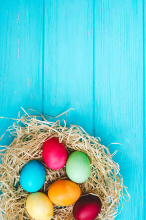 Easter eggs in the nest on blue wooden table background