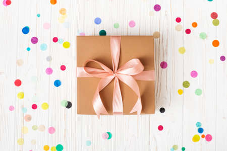 Gift box with pinkl ribbon on white background.with multicolored confetti Top view. Flat lay.の写真素材