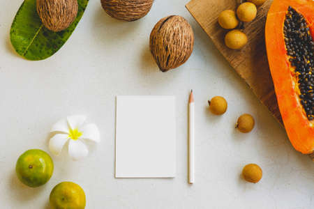 Creative layout made of tropical fruits and frangipani flower with white paper card note. Flat lay....