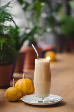 Pumpkin spiced latte in glass on wooden table in city cafe. Autumn, fall or winter hot drink concept.の写真素材